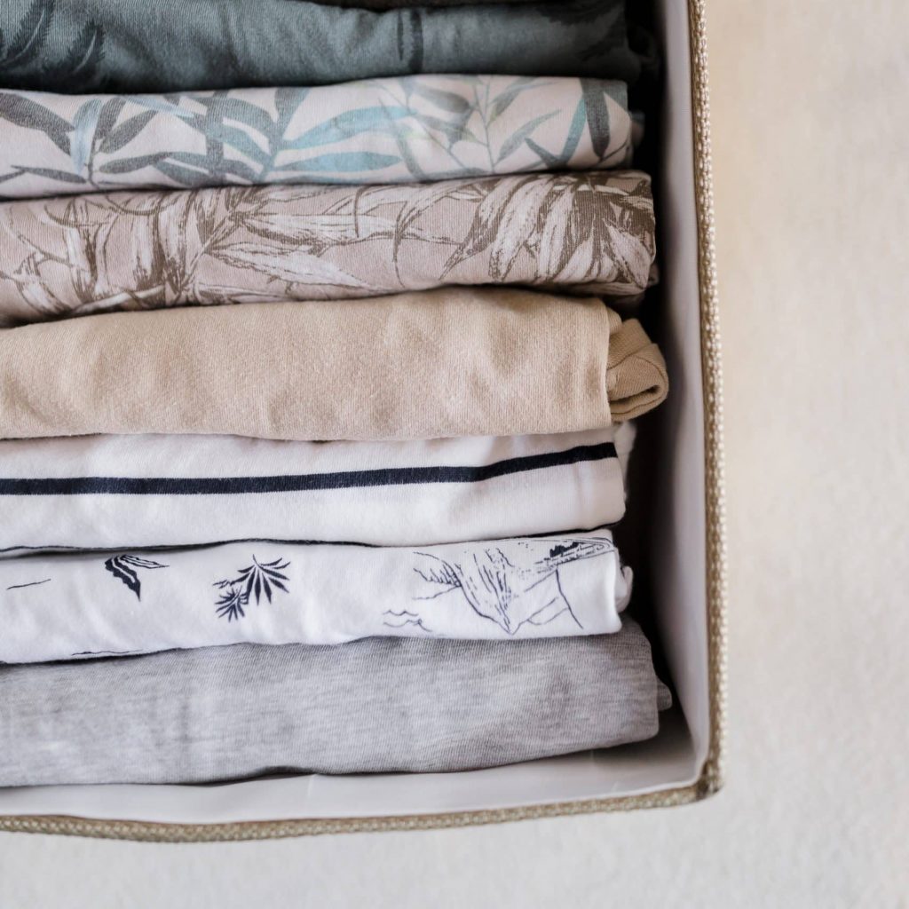 Vêtements pliés verticalement dans une boîte de rangement en tissu, méthode de pliage organisée.